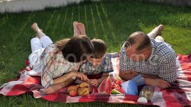 快乐的家庭成员趴在野餐的红毯子上